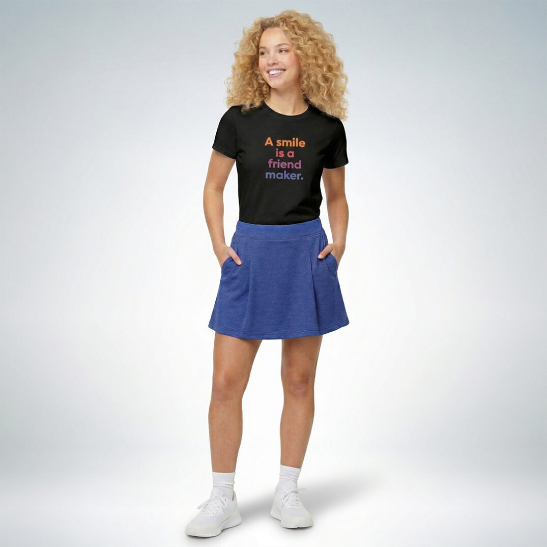 Weibliches Model trägt schwarzes T-Shirt mit „A smile is a friend maker“ Print und blauen Rock im farbenfrohen Casual-Look – Sinnstoff