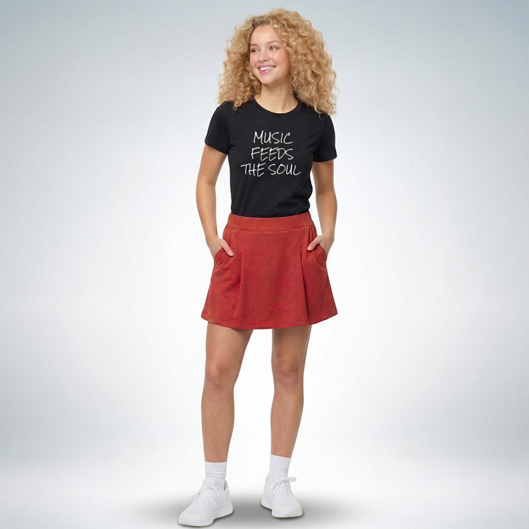 Weibliches Model trägt schwarzes T-Shirt mit „Music feeds the soul“ Print und roten Rock im modernen Casual-Look – Sinnstoff