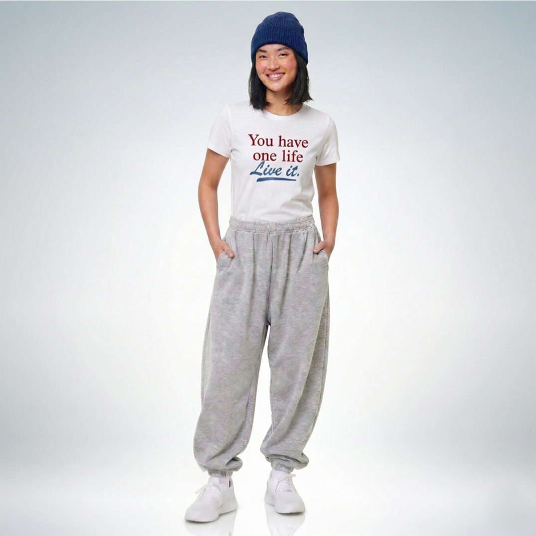 Weibliches Model mit blauer Mütze trägt weißes T-Shirt mit „You have one life – Live it“ Print und graue Jogginghose – Sinnstoff