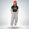 Weibliches Model mit orangefarbener Mütze trägt schwarzes T-Shirt mit „Push yourself“ Print und graue Jogginghose im sportlich-lässigen Look – Sinnstoff