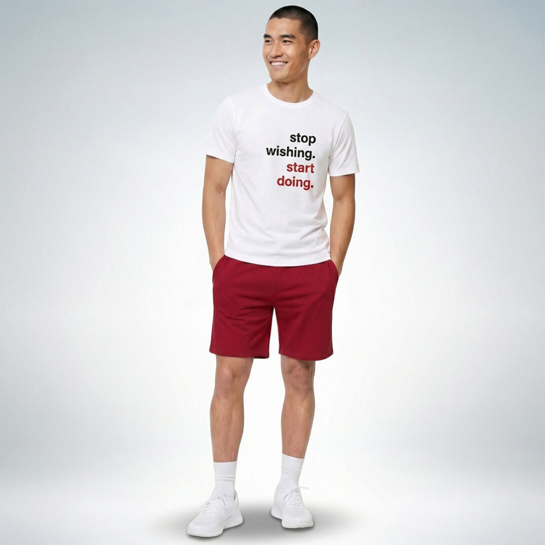 Männliches Model trägt weißes T-Shirt mit „Stop wishing. Start doing.“ Print und rote Shorts im sportlich-modernen Look – Sinnstoff
